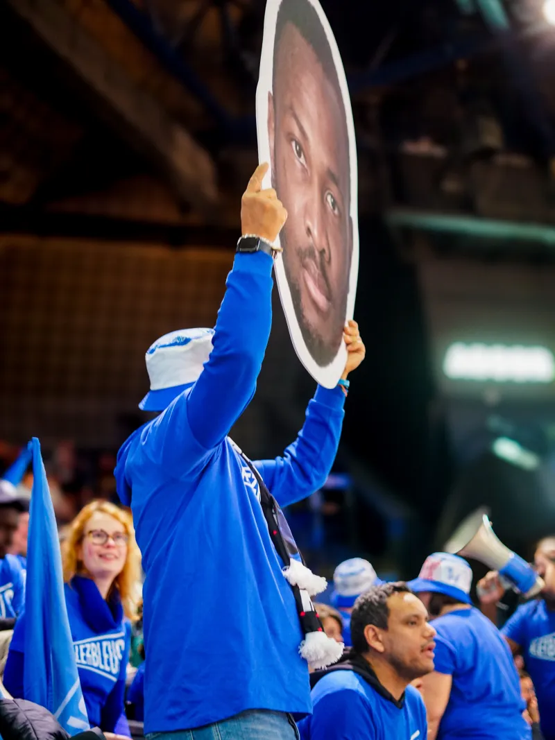 Leader d'ambiance brandissant une tête d'athlète géante en tribune