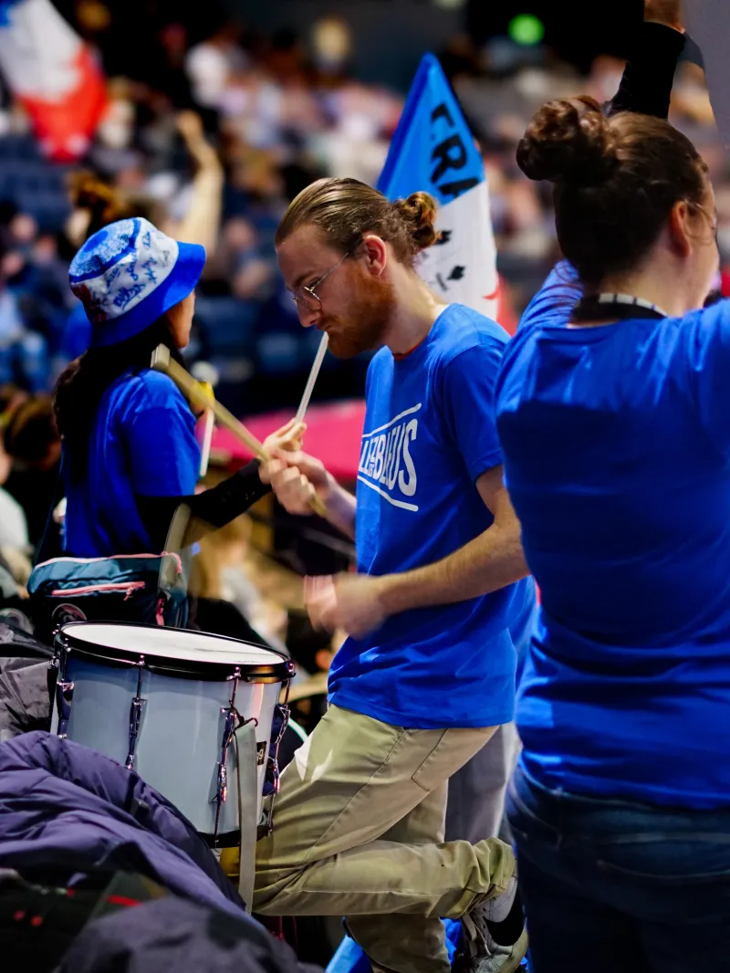Leader d'ambiance battant le tambour en tribune pour soutenir les athlètes 